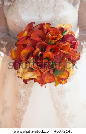 Bride holding wedding bouquet of red and orange calla lilies
