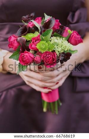 stock photo Bridesmaid holding wedding bouquet against purple dress