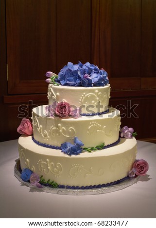Wedding cake with flowers on reception table with dramatic lighting