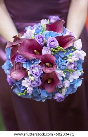 Bridesmaid holding blue and purple wedding bouquet against dress