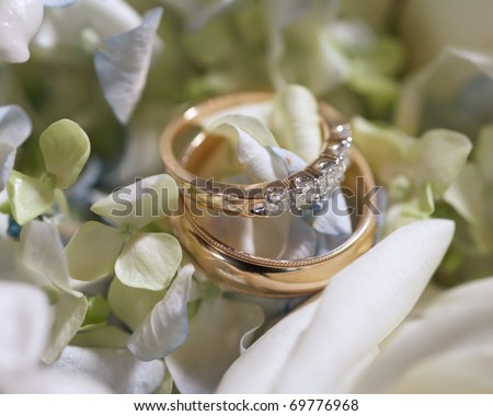 stock photo Pair or wedding rings on bouquet flowers focus on diamonds