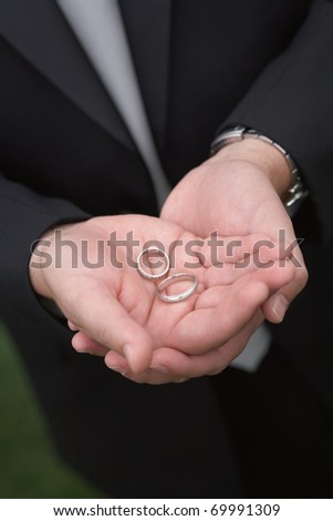 Man's hands holding wedding bands focus on rings