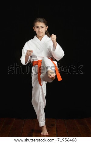Preteen girl exercising karate kick in dojo