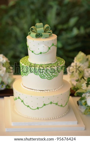 stock photo White and green wedding cake with flowers at reception