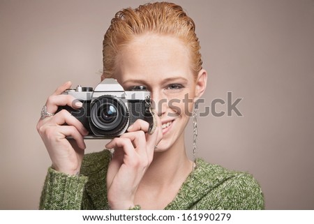 Pretty young woman photographer with old vintage camera taking picture