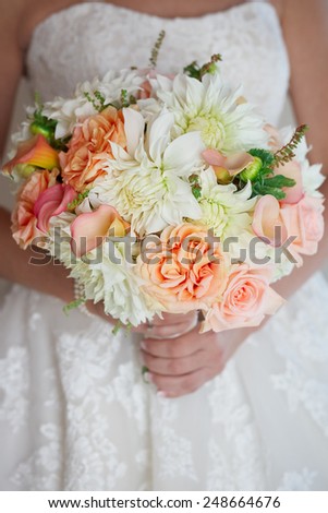 Bride holding wedding bouquet of roses and calla lilies