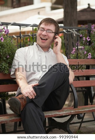 Laughing young man on phone conversation outside