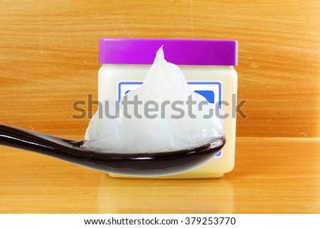 white petroleum jelly in spoon with jar