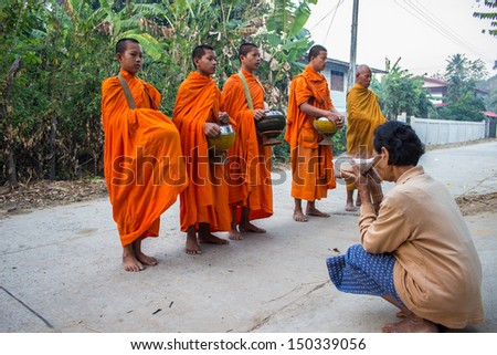 SURIN THAILAND-JANUARY 21: Unidentified  woman giving food to the monks and offering food to the monks.Thailand\'s traditional to merit by giving food to the monks.On January 21, 2013. Surin, Thailand.