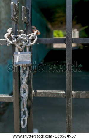 Silver pad lock and linked chain secure a black metal gate
