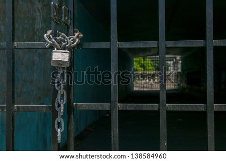 Silver pad lock and linked chain secure a black metal gate