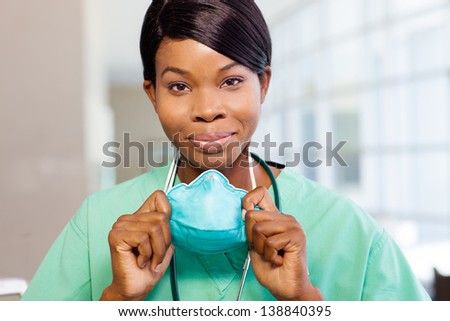 Smiling African American nurse at hospital work station lit brightly with phone and stethoscope.