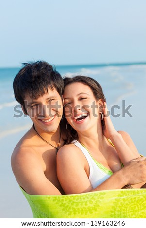 Medium shot of happy, smiling young latin couple on Beach wrapped in Green Towel. Ft. DeSoto Beach, Florida, USA.