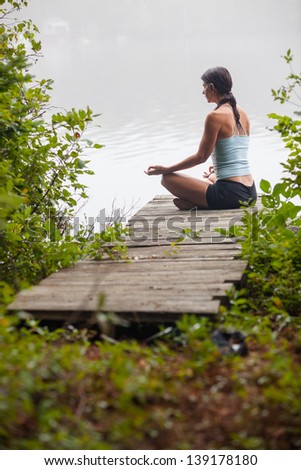 middle aged woman meditating on dock by a lake in the foggy morning, vertical composition, Surry Maine