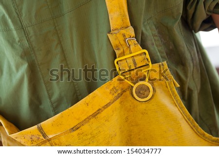 tight shot of yellow fishing overalls with green rain jacket