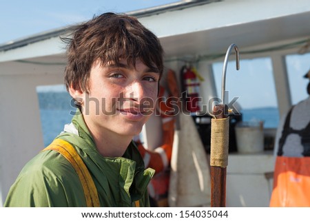 young, caucasian, brunette man on Boat Holding Hook to Catch Lobster, Maine, USA