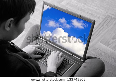 Adult woman typing on laptop. Selective focus on hands and screen with clouds.