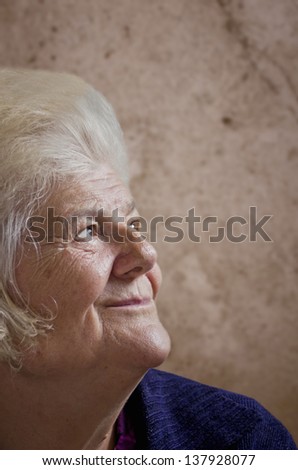 Portrait of an old woman on a vintage background. Dreaming the past.