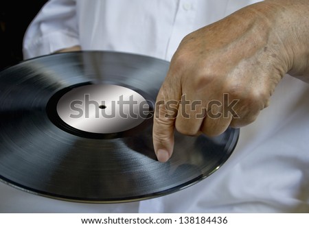 Person holding vinyl record pointing to the plate. Concept of making music.