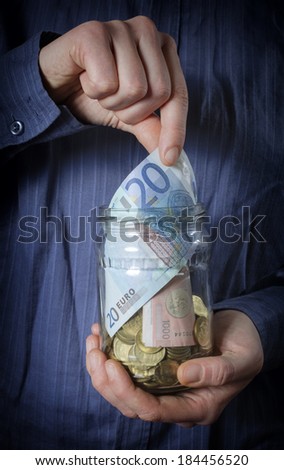 Jar of Money with hand picking up.