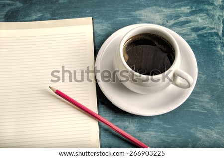 Open a blank white notebook, pencil and cup of coffee on the table
