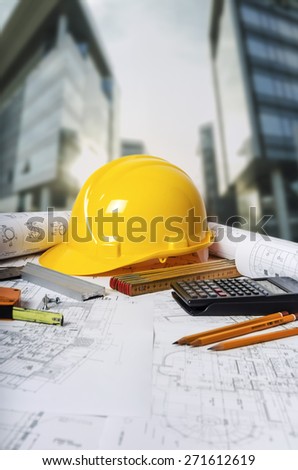 Engineer working table with safety helmet and writing instrument against construction site.