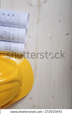 Construction helmet and heap of project drawings. Architectural design and construction background.