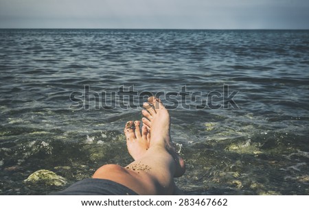 Man sunbathing on beach. Legs. Vintage effect.