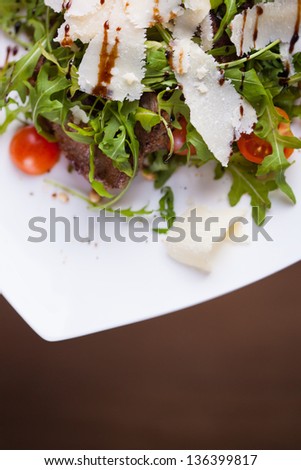 Beef steak fried in oil covered with cheese and rucola. Small tomatoes is in a plate. Shallow DOF. Developed from RAW; retouched with special care and attention;