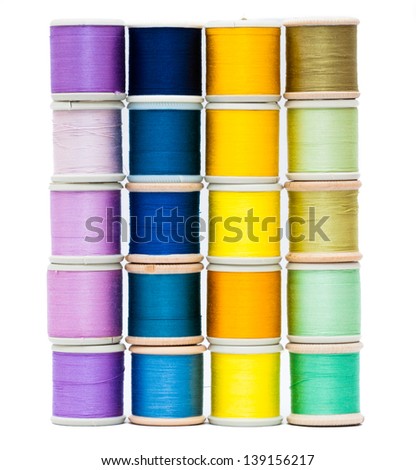 Four vertical stacks of vintage sewing threads isolated on white with shades of purple, blue, yellow and green