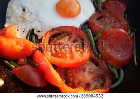 Tomatoes, egg and green garlic in a frying pan