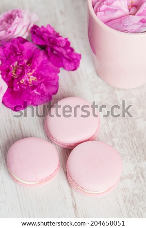 Tender pink macaroons and tea cup on white wood background, pastel colored, selective focus