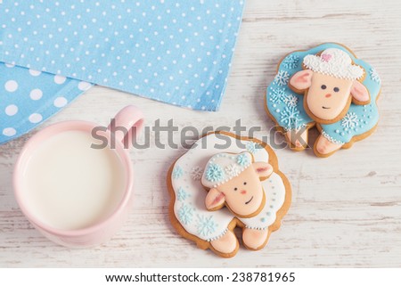 Two cute gingerbread sheep with cup of milk on white wooden background. Top view