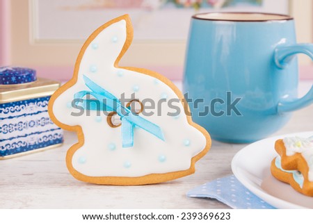 White Easter bunny rabbit gingerbread cookie with coffee mug on pastel pink background