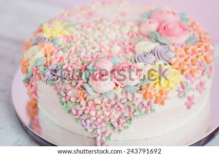 Pastel pink cake decorated with cream flowers. Pastel colored. Shallow focus.