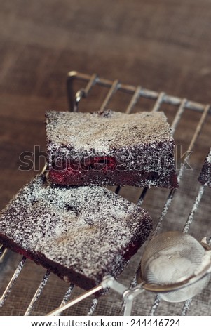 Chocolate brownies with raspberries and sugar powder on dark rustic background. Vintage instagram effect