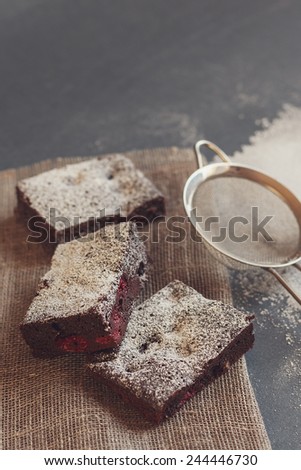 Chocolate brownies with raspberries and sugar powder on dark rustic background. Vintage instagram effect