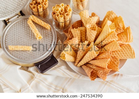 Empty waffle cones with vintage waffle-iron on table. Top view