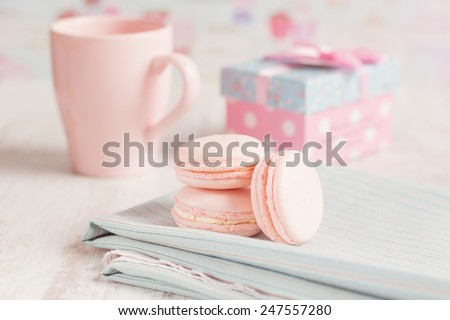 Pink macaroons with gift boxes and cup of coffee on background. Pastel colored