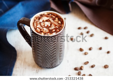 Cup of coffee with whipped cream and melted chocolate on white background with towel