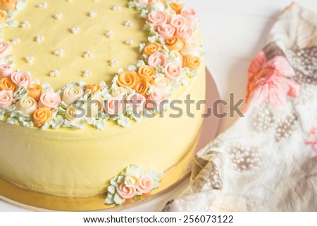 Pale yellow mousse cake with pastel cream flowers on white background