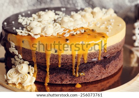 Romantic cake with chocolate glaze, cream flowers and  mango passion fruit mousse on retro background, 
vintage stylized photo