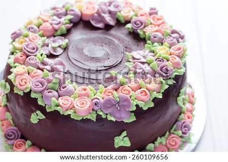 Homemade chocolate cake with colorful cream flowers on white background