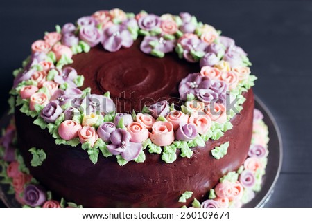 Homemade chocolate cake with colorful cream flowers on dark background