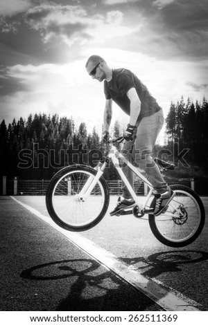 Young man jump on bicycle through the white line.  Black and white tonality