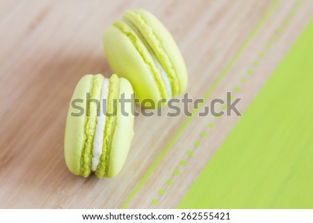 Top view of some green macaroons with cream ganache arranged diagonally on wooden background. Shallow focus