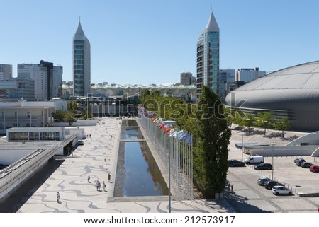 Lisbon, Portugal - August 07, 2014: Visitors comming in and out of the Vasco da Gama Shopping, Sao Rafael Tower in the back and Homem-Sol (Sun-Man) Sculpture. Parque das Nacoes.