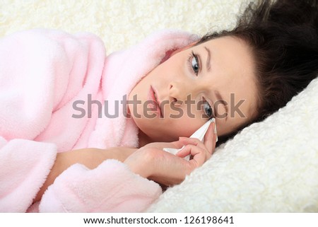 Crying young woman lies on a sofa and wipes away tears