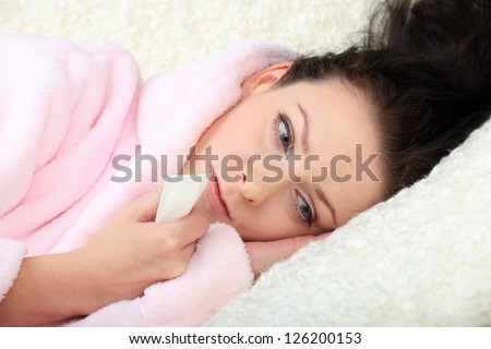 Sad young woman lies on a sofa and holds a tissue in a hand