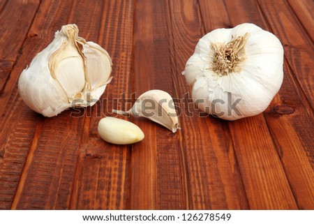 Garlic bulb, half of garlic bulb and peeled clove on wooden background